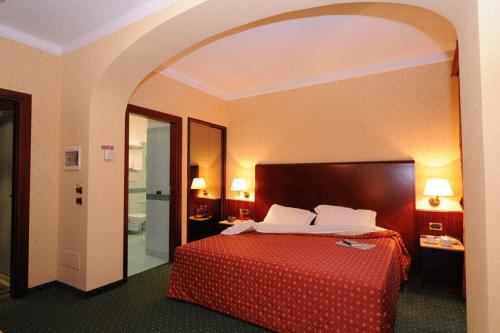 Habitación de hotel con cama con colcha roja en Hotel La Spia D'Italia, en Solferino