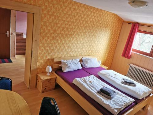 een slaapkamer met een bed met een paarse deken en een raam bij Pension Fernblick in Sankt Oswald