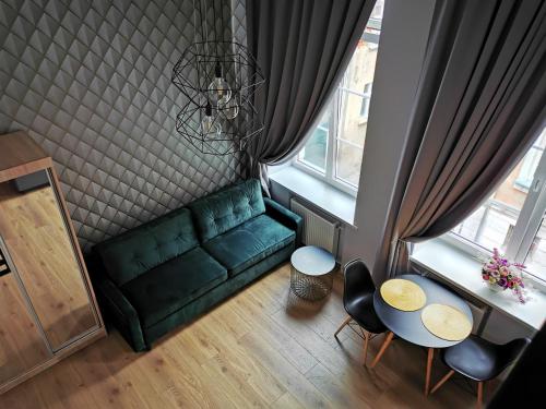 Old Town Loft في كلايبيدا: غرفة معيشة مع أريكة خضراء وطاولة