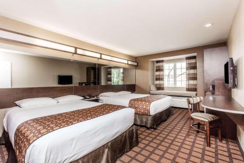 a hotel room with two beds and a desk at Microtel Inn & Suites by Wyndham Macon in Macon