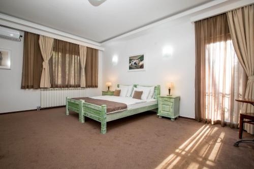 a bedroom with a bed and two tables and windows at Hotel Trim in Nikšić