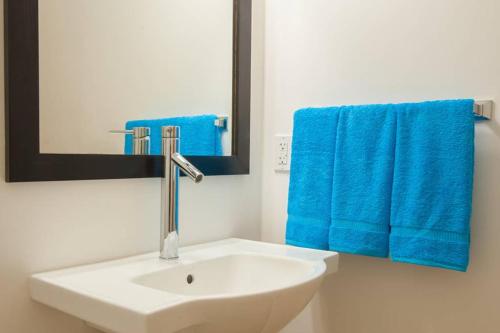 a bathroom with a white sink and blue towels at Vivaro Roatan North House in West End