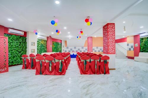 a banquet hall with red chairs and green plants at Hotel Mahadev Palace in Deoghar