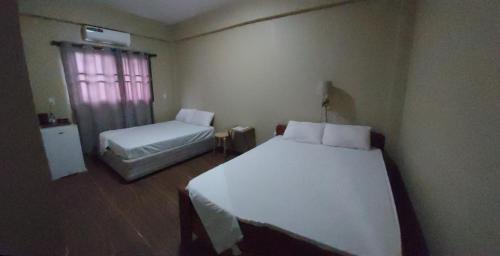 a bedroom with two beds and a window and a bed sidx sidx sidx at Waterland Suites in Paramaribo