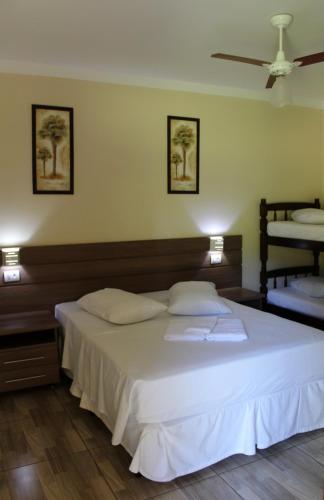 a bedroom with a large white bed with two pillows at Camping e Pousada Paiol in Águas da Prata