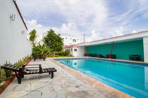 a swimming pool with benches next to a building at Hotel Colon Merida in Mérida