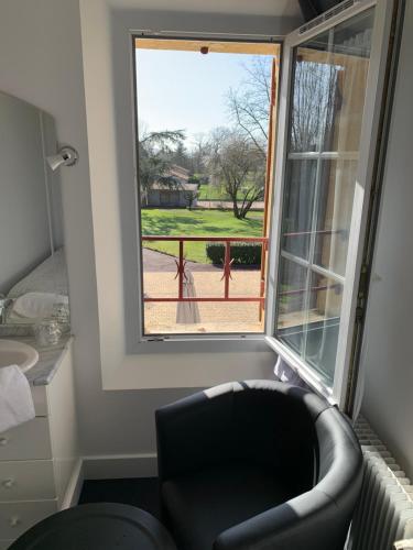 a living room with a chair and a large window at Le Melchior in Sainte-Terre