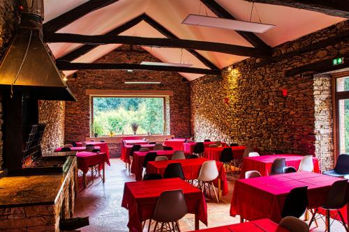 a restaurant with red tables and chairs in a room at La Bastide d'Albignac in Le Dourn
