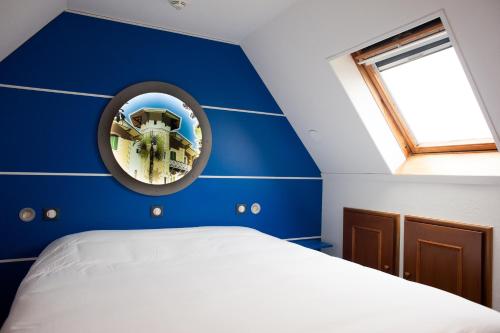 a blue room with a bed and a window at Hôtel Le Dauphin in Arcachon