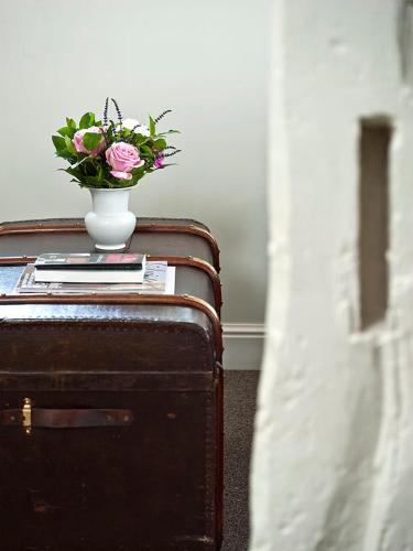a vase with flowers sitting on top of a suitcase at Country House Duinhof in De Haan