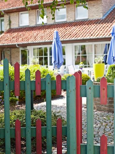 a green and red fence in front of a house at Country House Duinhof in De Haan