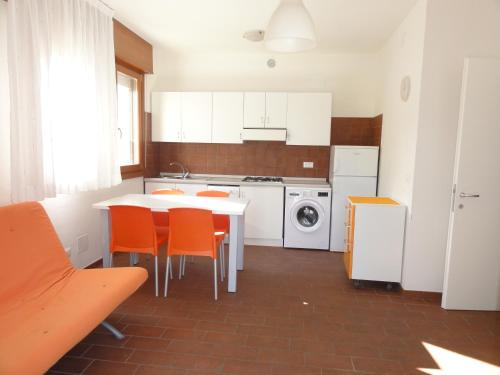 a kitchen with a table and orange chairs in it at Villa Mughetto in Bibione