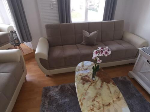 a living room with a couch and a table with flowers on it at Pension und Ferienwohnung Stadt Altenburg in Altenburg