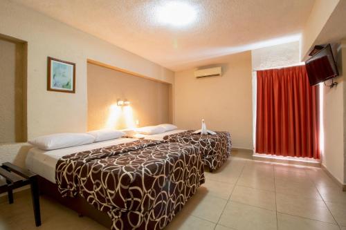 a hotel room with two beds and a red curtain at Hotel Colon Merida in Mérida