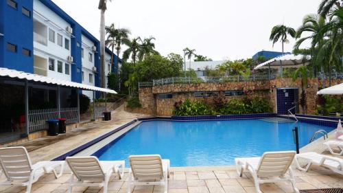 a large swimming pool with chairs and a building at Cafe e Almoço Hotel Thermas da Affego in Caldas Novas