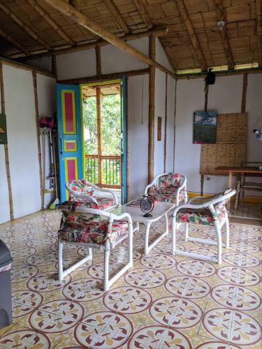 Zimmer mit 3 Stühlen, einem Tisch und einer Tür in der Unterkunft Hacienda Guayabal in Chinchiná