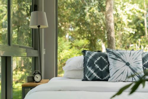 a bedroom with a bed with pillows and a window at The Box House in Tangalle