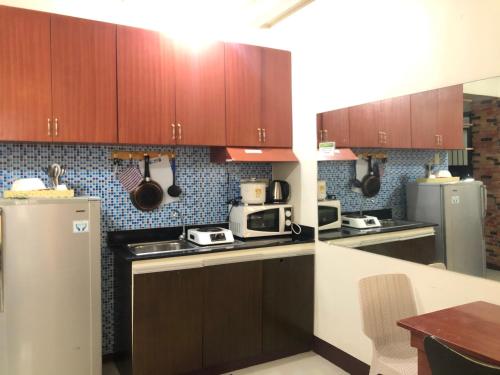 cocina con armarios de madera y nevera en Your City•Home Apartment, en Manila
