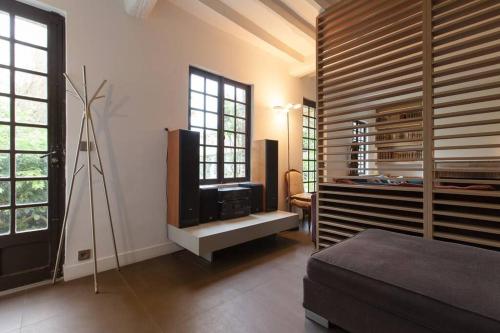 um quarto com uma cama, uma televisão e janelas em Cottage Normand em Montaure