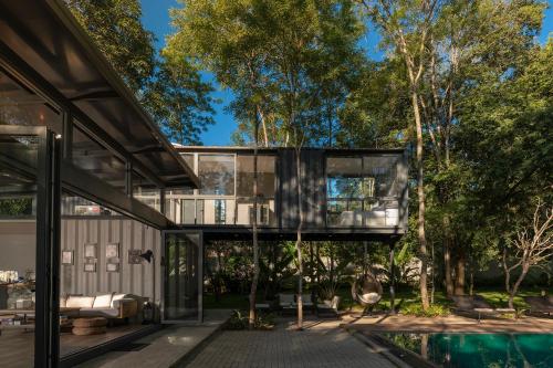 a glass house in the trees with a pool at The Box House in Tangalle