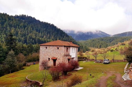 a small stone building in a field with a mountain at Elati Hills in Vytina