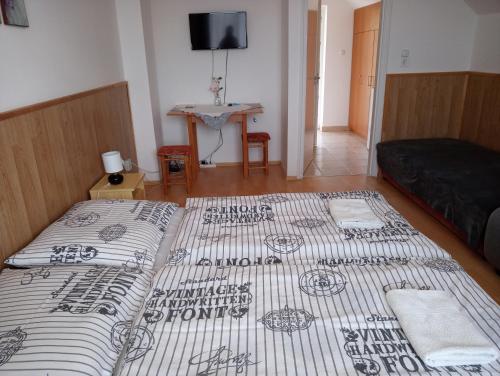 a bedroom with two beds and a couch in it at Napsugár Vendégház in Újudvar