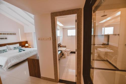 a bedroom with a bed and a bathroom with a sink at Maravista Hotel & Spa Ltda in Búzios