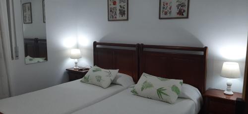 um quarto com 2 camas com lençóis brancos e almofadas em Pensión CASA LEÓN em Santoña