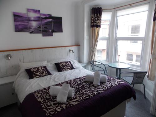 a bedroom with a bed and a table and windows at Ocean House - Weymouth in Weymouth