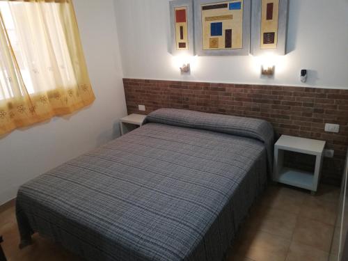 1 dormitorio con 2 camas y pared de ladrillo en Vandaele Home, en Corralejo
