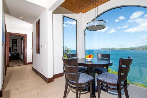 a dining room with a table and chairs and a large window at 360 Splendor Del Pacifico Residences in Playa Flamingo