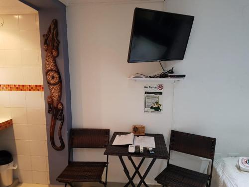 a small table with chairs and a tv on a wall at Posada J&J Forbes - 1 in San Andrés