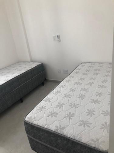 2 Betten in einem kleinen Zimmer mit ermottermott in der Unterkunft APTO CHURRASQUEIRA, Capitania Varam, Pitangueiras, piscina, 100 m da praia, 2 dormitórios, 2 vagas de garagem in Guarujá