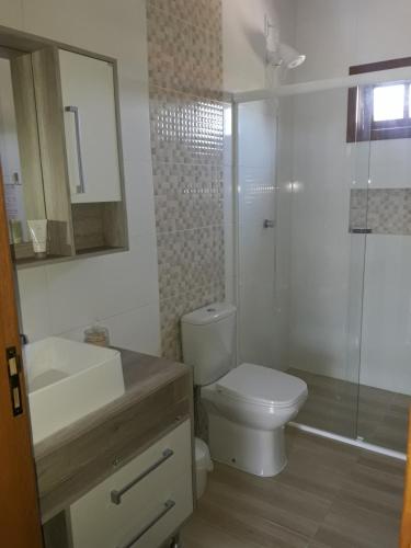uma casa de banho com um WC, um chuveiro e um lavatório. em Casa Aconchegante Praia do Rosa Ibiraquera SC em Imbituba