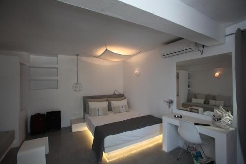 een witte slaapkamer met een bed, een bureau en een spiegel bij Edem Suites in Ándros