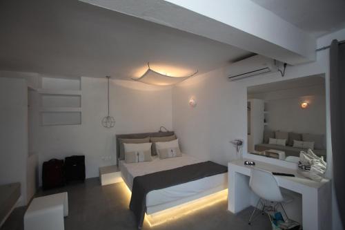 Habitación blanca con cama, escritorio y espejo. en Edem Suites, en Ándros