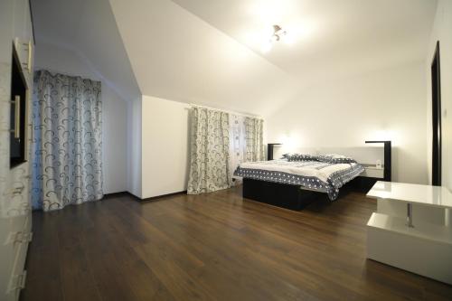 um quarto com uma cama e piso em madeira em Pensiunea Natalia em Toteşti
