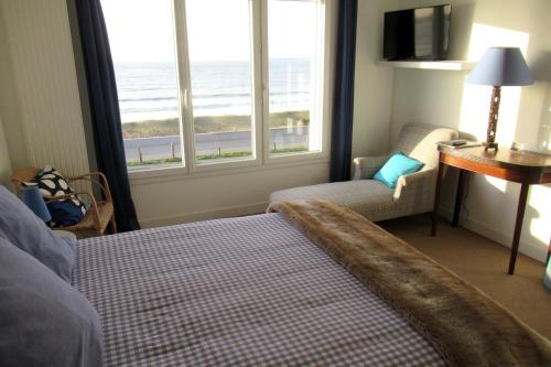 une chambre d'hôtel avec un lit, une chaise et des fenêtres dans l'établissement Chambre d'Hôtes La Dune - face mer, à Saint-Michel-Chef-Chef