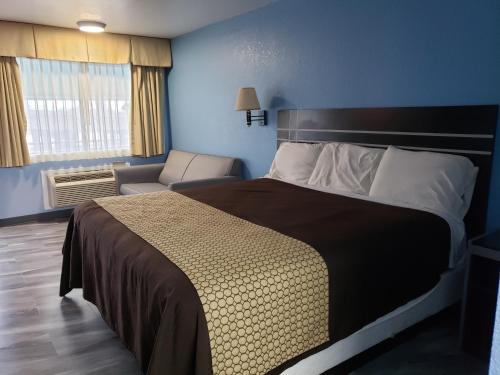 um quarto com uma cama grande e uma cadeira em Regency Inn Motel by the Beach em Corpus Christi
