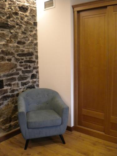 a blue chair in a room with a stone wall at Casa de Aldea Araceli in Berducedo