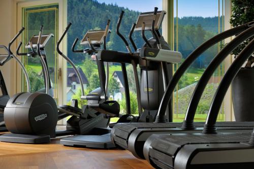 a row of cardio machines in a gym with a window at Wellness & Genuss Resort - Engel Obertal in Baiersbronn