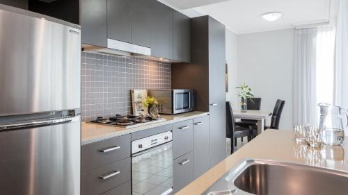 a kitchen with a sink and a stove top oven at Oaks Brisbane Casino Tower Suites in Brisbane