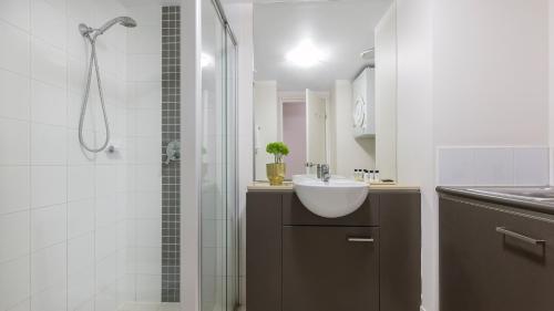 a white bathroom with a sink and a shower at Oaks Brisbane Casino Tower Suites in Brisbane