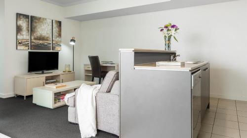 a living room with a couch and a tv at Oaks Brisbane Casino Tower Suites in Brisbane
