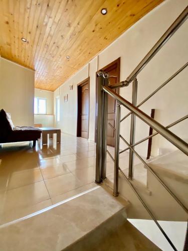 a living room with a wooden ceiling and a staircase at Hotel Toni in Gudauri