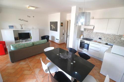 a kitchen and living room with a black table and chairs at Sa Mirada Apartments in Villasimius