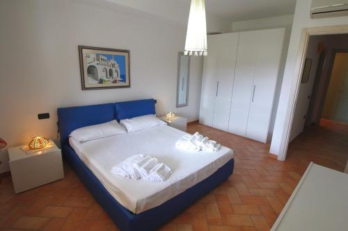 sypialnia z niebieskim łóżkiem i ręcznikami w obiekcie Sa Mirada Apartments w mieście Villasimius