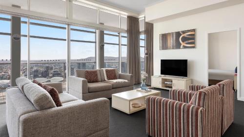 a living room with a couch and chairs and a tv at Oaks Brisbane Casino Tower Suites in Brisbane
