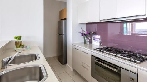 a kitchen with a sink and a stove top oven at Oaks Brisbane Casino Tower Suites in Brisbane