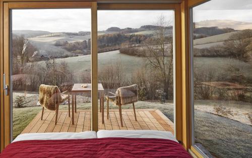 a bedroom with a large window with a table and chairs at Triad Wiener Alpen Bett DZ in Bad Schönau
